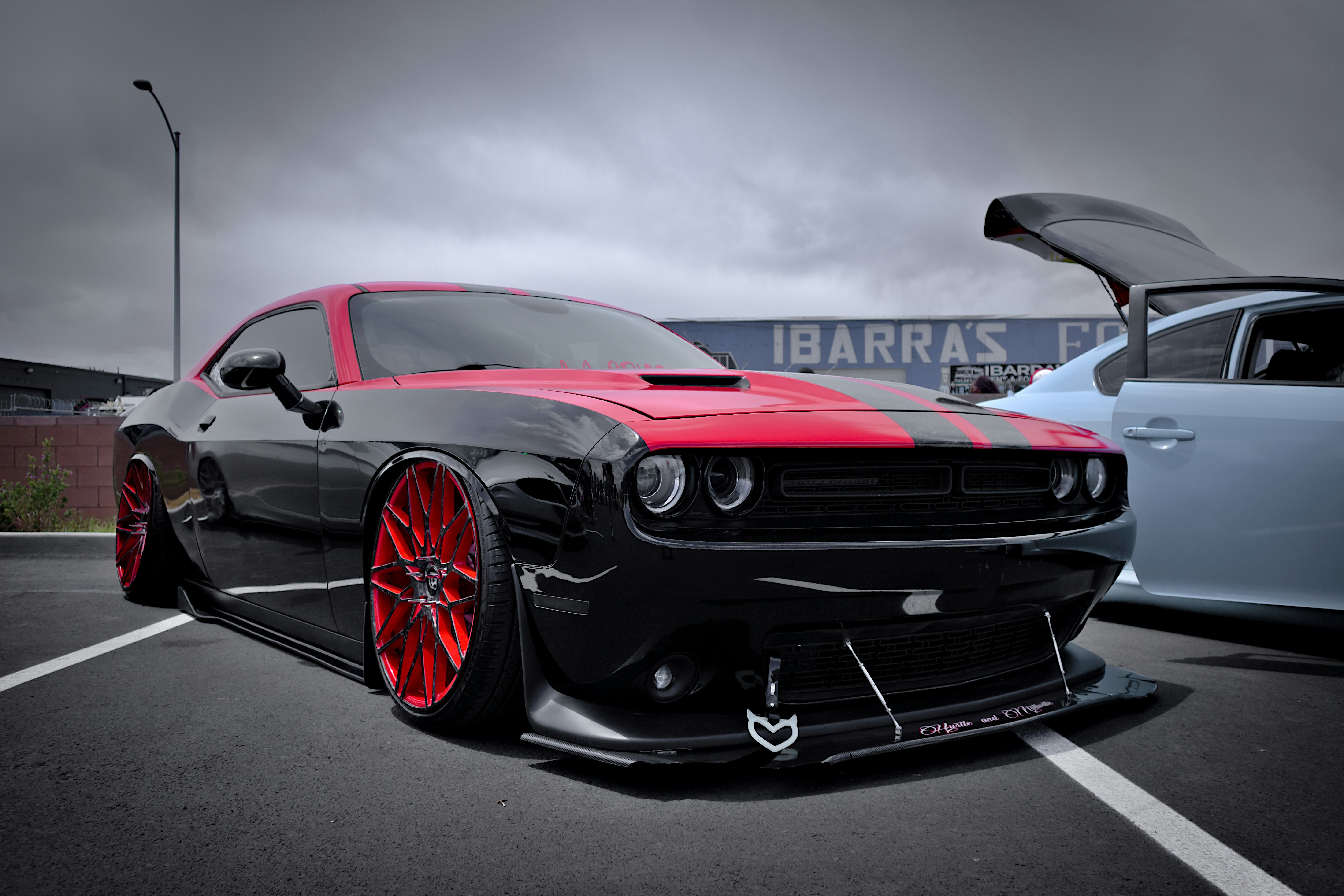 A black Dodge Challenger with red striping and a modified bumper.